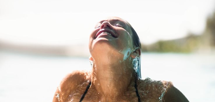 Beautiful woman in the pool looking up in a sunny day