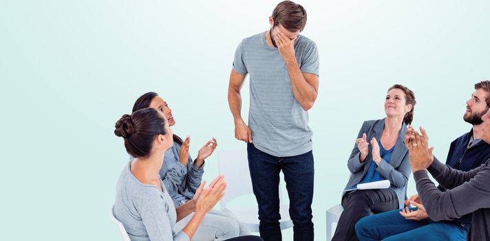 Rehab group applauding delighted man standing up against blue background