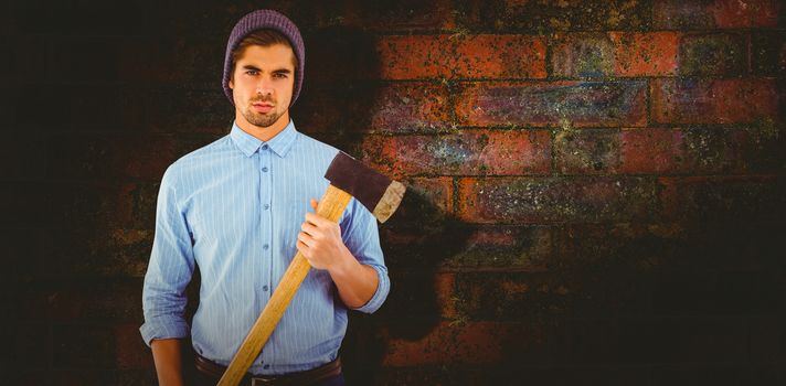 Portrait of serious hipster holding axe against texture of bricks wall