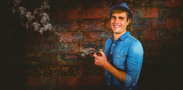 Cheerful hipster holding pipe against texture of bricks wall