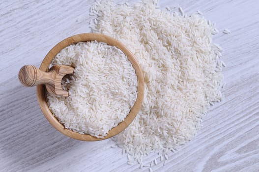Close-up of white rice in bowl and on blue wooden table. From above
