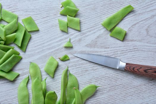 Green peas cut on wooden table with knife