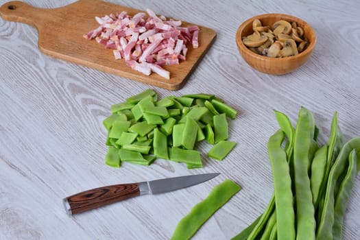 Mushrooms, sliced bacon and cut green peas on wooden table