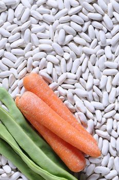 Close-up of carrot and green peas on white kidney beans. From above