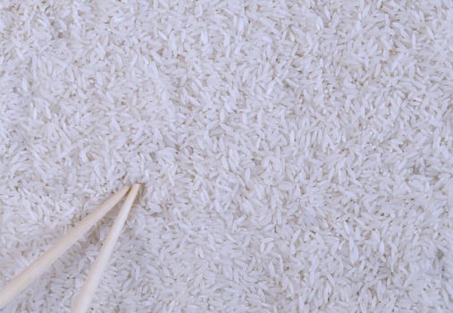 Close-up of white rice and wooden sticks. From above