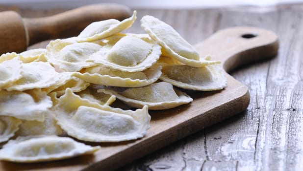 Close-up of homemade raw ravioli on wooden board in daylight