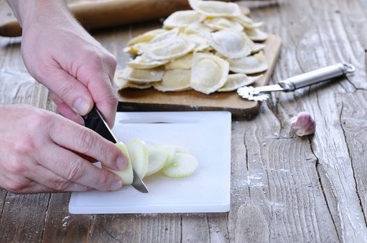 Unrecognizable man preparing food on board with knife