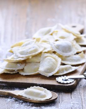 Close-up of homemade raw ravioli on wooden board in daylight