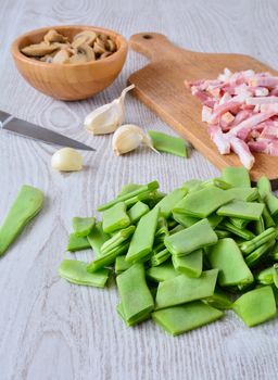 Mushrooms, sliced bacon and cut green peas on wooden table