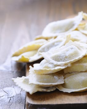 Close-up of homemade raw ravioli on wooden board in daylight