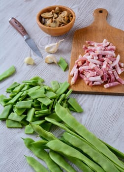 Mushrooms, sliced bacon and cut green peas on wooden table