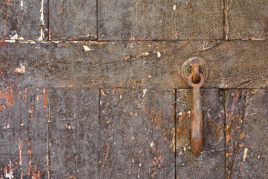 Close-up of worn out shabby wooden door with rusty metal doorbell