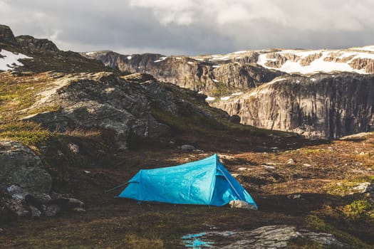 Tourist's tent stands in the mountains. Summer sunrise above beautiful rocks in Norway.