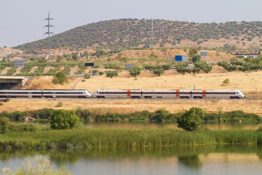 Automotive train of travelers, with diesel traction used as regional transport in Spain as it passes through Mérida with the Guadiana River in the foreground