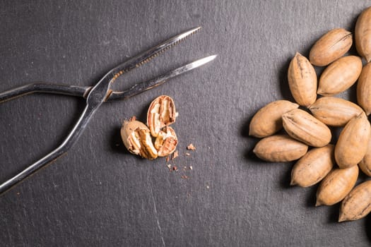 Pecan nuts with nutcracker on slate stone