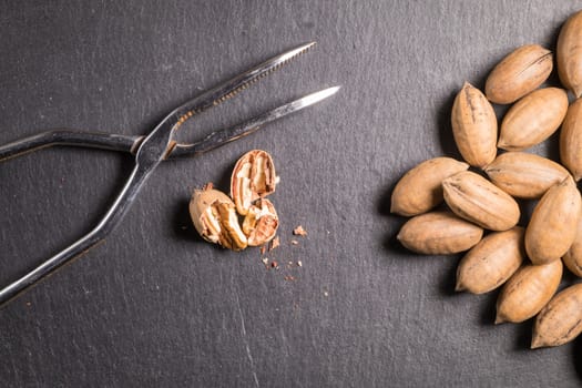 Pecan nuts with nutcracker on slate stone