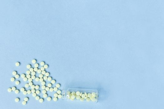 yellow tablets on a pastel blue background. Tablets and a glass bottle on a blue background. Medicine, healthcare and tablets concept. Flatley. The view from the top. copyspace for text.