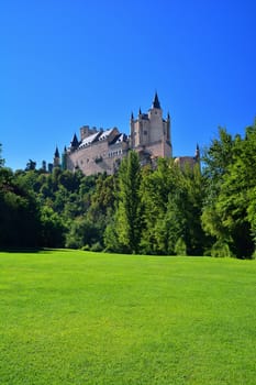 Idyllic view on bright landscape with famous Alcazar in Segovia, Spain against of blue sky in sunlight