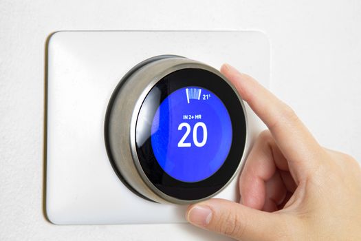 A person cooling down Home Air Conditioning, temperature is on centigrade celsius metrics using a smart thermostat on a white wall.