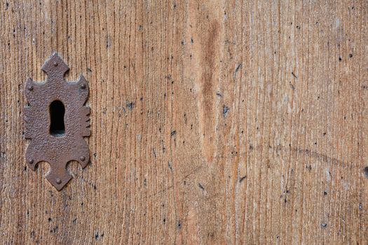 Close-up of metal decorative keyhole on wooden textured door