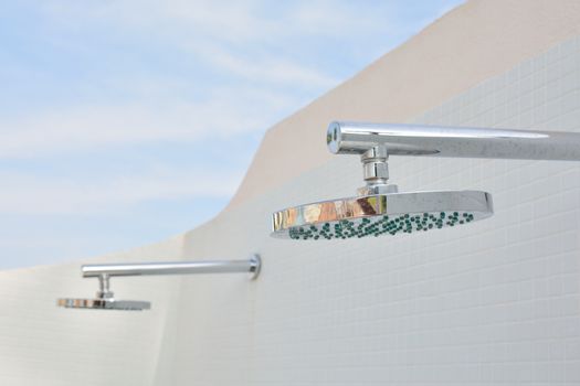 Close-up of metal shower hanging on white glazed tiled wall. Copy space