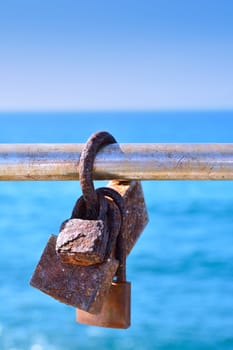 Close-up of rusty love locks hanging on metal railing in sunlight