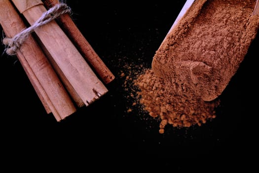 Close-up of cinnamon sticks tied with rope and powdered of black background.Copy space.