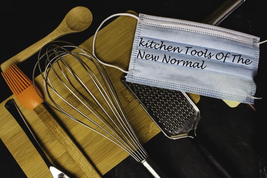 Lettering of the new normal on kitchen utensils and tools. Face mask in modern kitchen.