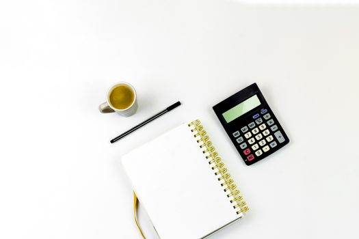 Laptop, Notebook and Office Supply Items on white Work Desk with coffee and calculator