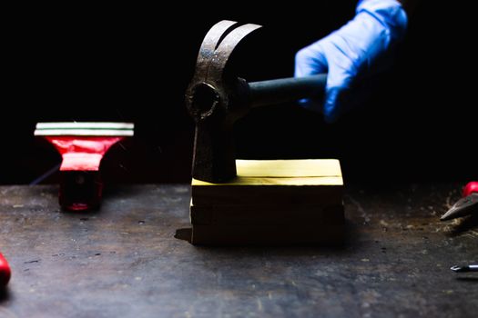 hand with blue gloves hitting with hammer wooden box, concept of repair, maintenance and crafts in a black background.