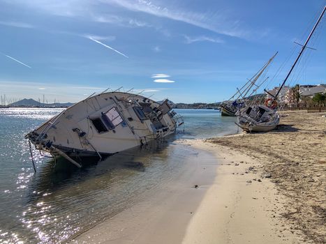 Several boats stranded on the beach after a storm. On a sunny day with few clouds.