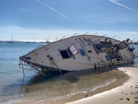 Boat stranded on the beach after a storm. On a sunny day with few clouds.