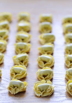 Preparing homemade tortellini on wooden table in the kitchen.