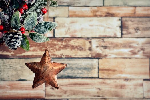 Close-up of holly berry with hanging bronze xmas star against of brickwall