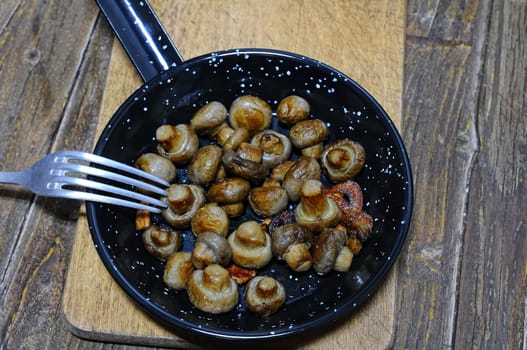 Garlic mushrooms in the pan on the kitchen table.