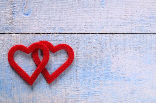 Two red hearts fabric over wooden table.