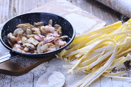 Preparing homemade tagliatelle on wooden table in the kitchen.