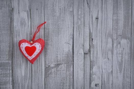 Close-up of handmade red valentine heart pinned on wooden background. Copyspace.