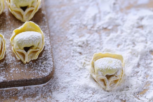 Preparing homemade tortellini on wooden table in the kitchen.