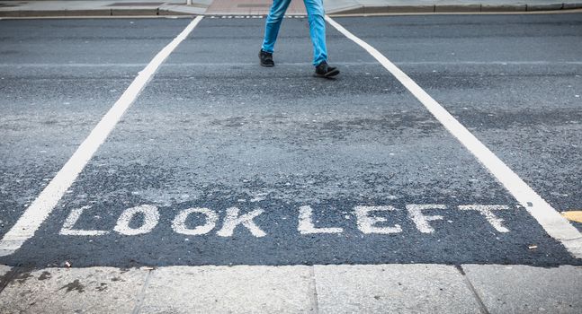 Look Left painted in white on the road on a pedestrian crossing in the city center on a winter day