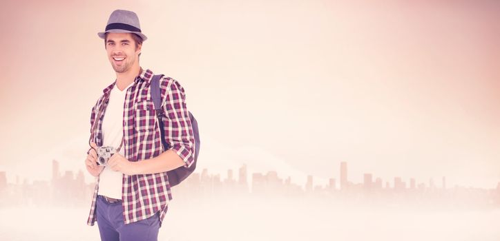 Portrait of happy man holding camera against large city on the horizon