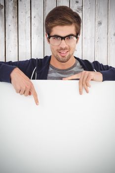Portrait of man wearing eyeglasses pointing on billboard against wooden planks