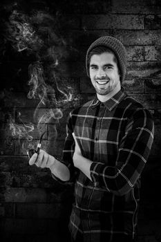 Portrait of happy man holding smoking pipe against texture of bricks wall