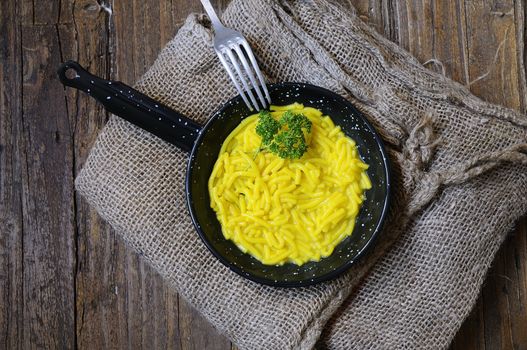 Noodles in a pan over wooden table in the kitchen