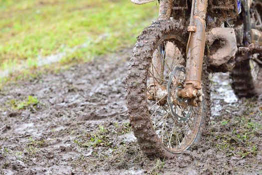 Close-up of dirty wheel of motocross bike in mud. Bokeh.
