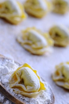 Preparing homemade tortellini on wooden table in the kitchen.