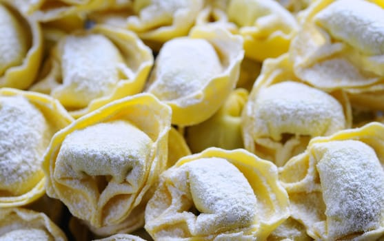 Preparing homemade tortellini on wooden table in the kitchen.