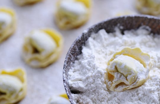 Preparing homemade tortellini on wooden table in the kitchen.