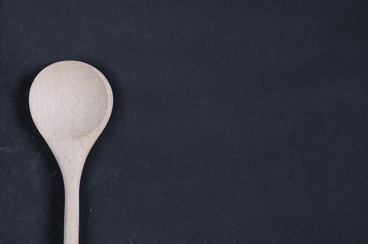 Wooden spoon on a blackboard with space for writing.