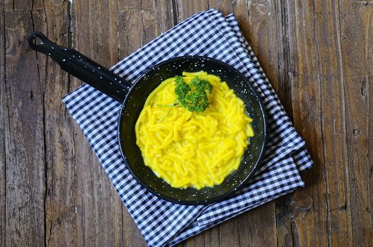 Noodles in a pan over wooden table in the kitchen